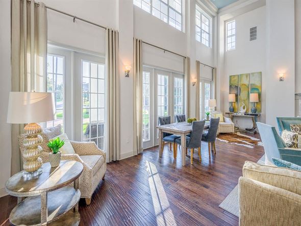 Tallahassee apartment for rent - Resident clubhouse with high windows, wood flooring, high ceiling, and several chairs and tables at Evergreens at Mahan apartments  in Tallahassee, FL