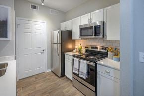 Tallahassee apartment for rent - Tallahassee FL apartment kitchen area with stainless steel appliances, shaker-style cabinetry, and wood-designed flooring at Evergreens at Mahan