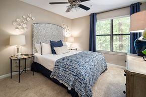 Canton apartment for rent - Furnished model bedroom with large window, ceiling fan, and carpet flooring at Heritage at Riverstone