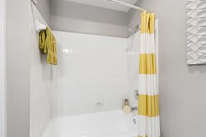 Pikesville apartment for rent - A white and yellow striped shower curtain hangs over a white bathtub.