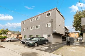 San Jose apartment for rent - a large gray building with cars parked in front of it