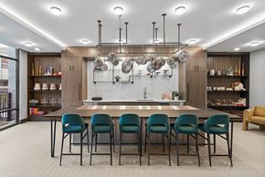Hackensack apartment for rent - a kitchen with a long island with blue chairs and pots and pans hanging above it
