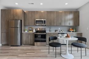 Bayonne apartment for rent - A modern kitchen with a refrigerator, microwave, oven, and a dining table with chairs.