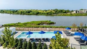 Bayonne apartment for rent - A pool area with blue umbrellas and a view of a river.