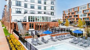 Bayonne apartment for rent - A modern building with a pool and lounge chairs.