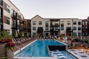 Montvale apartment for rent - A swimming pool is surrounded by lounge chairs and umbrellas in front of apartment buildings.