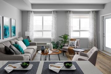 West Kelowna apartment for rent - A modern living room with a grey sofa, a coffee table, and a dining table with chairs.