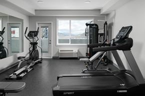 Kamloops apartment for rent - A black and white photo of a gym with a treadmill in the foreground.
