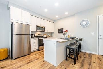 Chilliwack apartment for rent - A modern kitchen with a stainless steel refrigerator and a white island with bar stools.