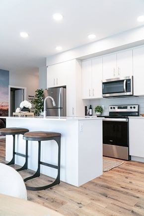 Colwood apartment for rent - A modern kitchen with white cabinets and a wooden floor.