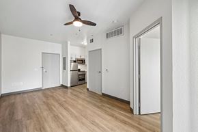 Las Vegas apartment for rent - A room with a ceiling fan and a kitchen area in the background.