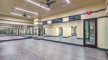 Expansive fitness center a wooden floor and a ceiling fan