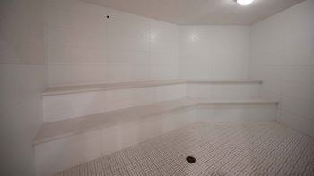 A white tiled room with a drain in the middle.