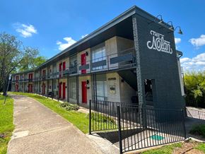 Birmingham apartment for rent - The Nolan Apartments building has a black fence and a green lawn in front.