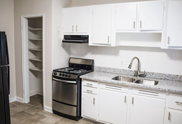 Birmingham apartment for rent - A kitchen with white cabinets and a black stove top oven.