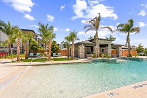 Sarasota apartment for rent - A swimming pool surrounded by palm trees and a house in the background at The Concord Luxury Apartments, Sarasota, FL