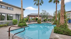 Peoria triplex for rent - A swimming pool surrounded by palm trees and a building at Grandstone at Sunrise, Peoria, AZ