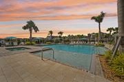 North Venice triplex for rent - A swimming pool surrounded by palm trees and a sunset sky. at The Sophia, Venice, FL, 34275