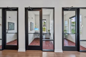 Three black doors open to a hallway with a red floor.