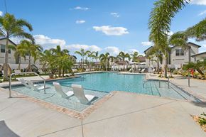 North Port triplex for rent - A swimming pool surrounded by palm trees and lounge chairs at The Hadley - North Port, FL Apartments, North Port