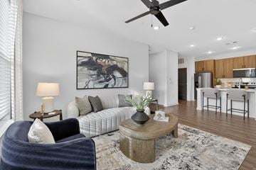 Colorado Springs apartment for rent - A living room with a blue chair, a white couch, and a large painting on the wall.