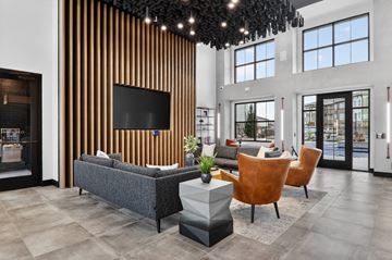 Nampa apartment for rent - A modern living room with a grey sofa, a wooden chair and a TV mounted on a wooden wall.