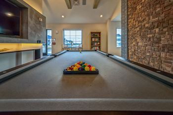 A billiards room with a pool table and a basket of balls