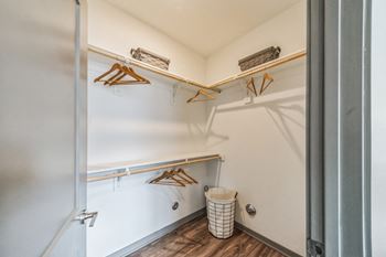 A walk in closet with shelves and a trash can in a room with a door