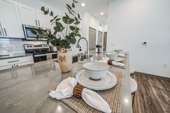 An open kitchen and dining area with white cabinets and stainless steel counter tops