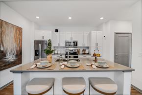 Wyoming townhouse for rent - a kitchen with white cabinets and a island with four chairs at The BLVD at Wilson Crossings, Michigan, 49418