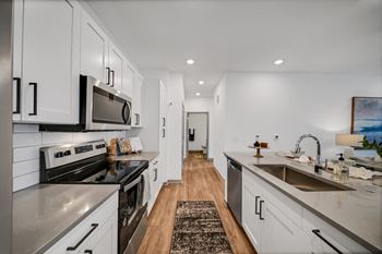 An open kitchen with stainless steel appliances and white cabinets
