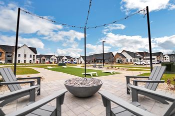 A park with benches and fire pits with houses in the background
