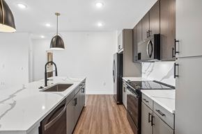Colorado Springs apartment for rent - A modern kitchen with dark wood cabinets and white countertops.