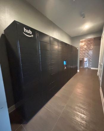 A long hallway with black lockers and a tv on the wall