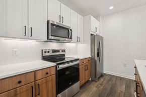 Rockledge apartment for rent - A kitchen with wooden cabinets and stainless steel appliances. at The Junction at Rockledge Apartments, Rockledge, FL