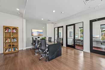 A room with a black table and chairs with a view of the outside.