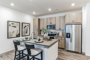 A kitchen with stainless steel appliances and a island with two chairs