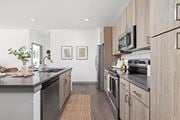 Ellenton apartment for rent - a modern kitchen with stainless steel appliances and wooden cabinets at Palm Grove in Ellenton, FL 34222