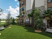 Sarasota apartment for rent - A large grassy area in front of a building with a bench and a tree.