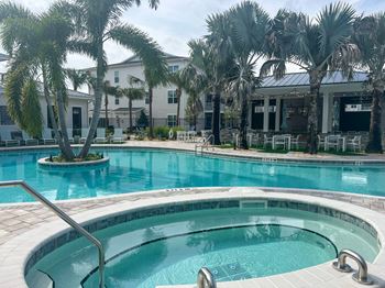 A large swimming pool with palm trees in front of a building