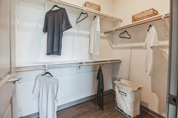 A walk in closet with white walls and wooden floors