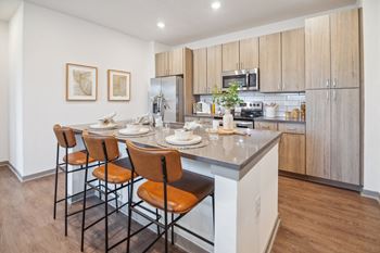 A kitchen with a large island with stools and a table with chairs