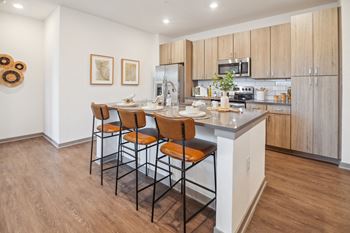 A kitchen with a island with four stools in front of it