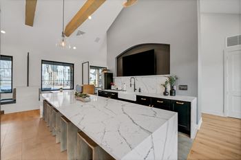 The kitchen has a large island with marble counter tops and a large tv