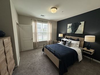 A master bedroom with a large bed and a black accent wall