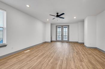 An empty living room with white walls and a ceiling fan
