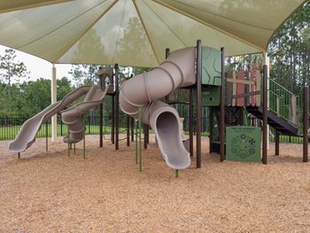 Shaded playground with tube slides and climbing structure