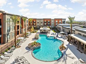 Buckeye apartment for rent - A large swimming pool surrounded by lounge chairs and palm trees at The Maddox Luxury Apartments, Buckeye, AZ, 85326