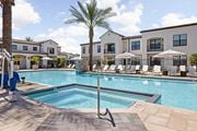 San Tan Valley apartment for rent - A pool surrounded by lounge chairs and umbrellas with a building in the background.at Stella, San Tan Valley Arizona