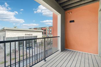 A balcony with a view of a fitness center and a building